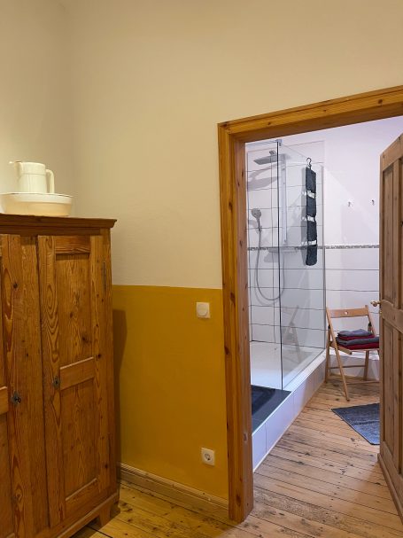 Blick ins Badezimmer Holzschrank in einem Raum mit orangefarbener Wand und Blick auf ein Badezimmer.