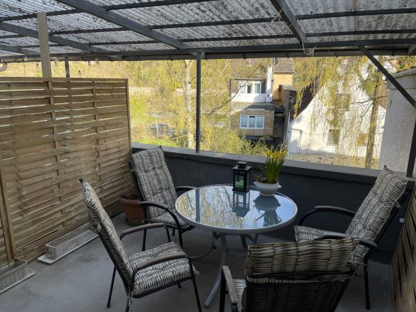 Sitzbereich auf der Terrasse Gemütlicher Balkon mit Tisch, Stühlen und Blick auf das umliegende Wohngebiet.