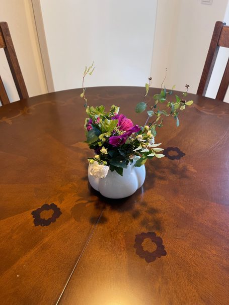 Esstisch Bunte Blumen in einer weißen Vase auf einem Holztisch.