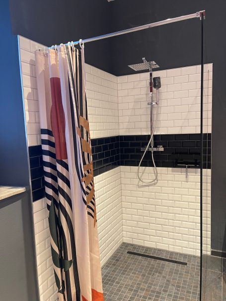 Großzügige barrierefreie Dusche Moderne Duschkabine mit transparenten Vorhängen und hellen Fliesen.