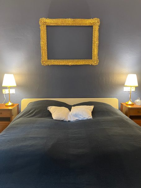 Schlafzimmer mit 180er Bett Zweifarbiges Schlafzimmer mit einem Bett, zwei Nachttischen und einem leeren Rahmen an der Wand.