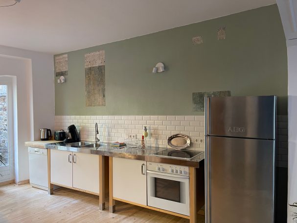 Küchenzeile mit Spülmaschine und großem Kühlschrank Küchenzeile mit Edelstahlgeräten, Waschbecken und grünem Wandanstrich.