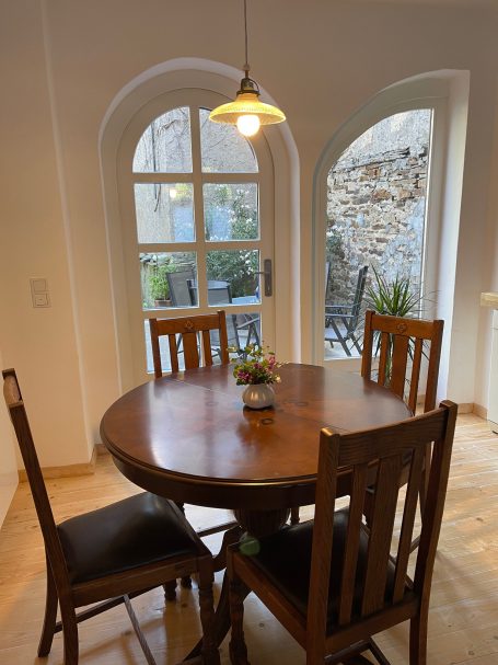 Essbereich mit ausziehbaremn Tisch und Zugang zum Garten Holztisch mit Stühlen in einem hellen Raum, Fenster mit Blick auf einen Garten.